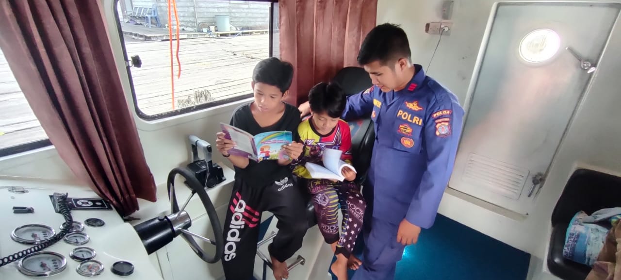Bangkitkan Semangat Baca , Personel Kapal XVIII-2002 Ditpolairud Ajak Anak Bantaran Sungai Membaca Buku Di Kapal